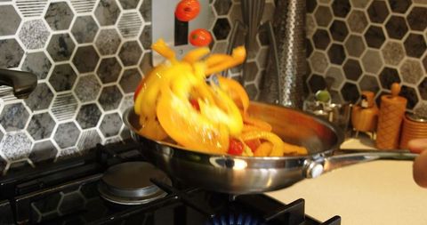 Colorful vegetables tossed in pan over stove