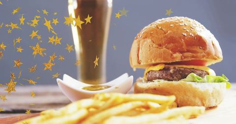 Showcasing sesame bun cheeseburger with melted cheese, fries and festive gold confetti