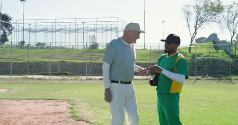 Coach mentoring player on baseball field during practice offering guidance and teamwork tips