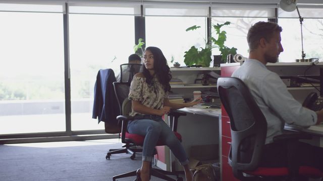 This video shows diverse professionals working together in a modern open-plan office. Ideal for depicting collaboration and teamwork in a business environment. Could be used in articles or advertisements about modern workplaces, technology in offices, or business productivity.