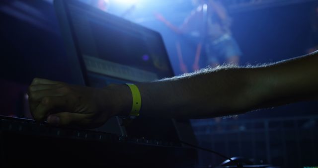 DJ is mixing music using equipment at a nightclub with strong lighting effects. Ideal for themes around nightlife, music industry, DJ culture, live performances, and entertainment.