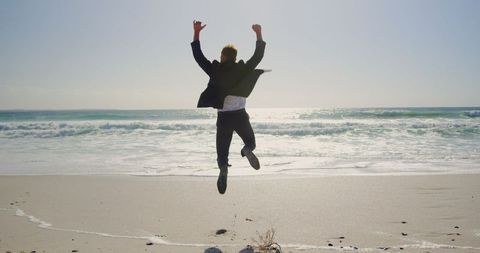 Joyful Businessman Leaping by Ocean Shoreline