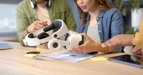 Design team testing white vr headset prototype while collaborating in modern workspace