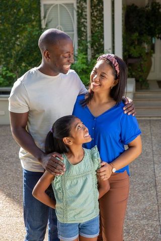 Happy family standing outside cozy home with greenery