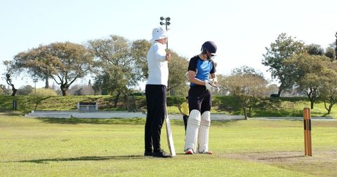 Umpire and Cricketer Preparing on Sunny Day at Cricket Ground