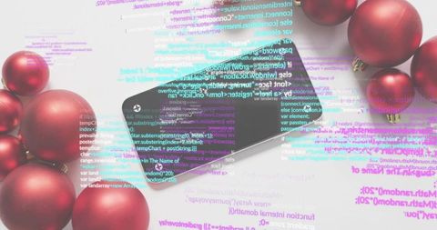 Black smartphone reflecting colorful code overlay among red holiday ornaments flatlay