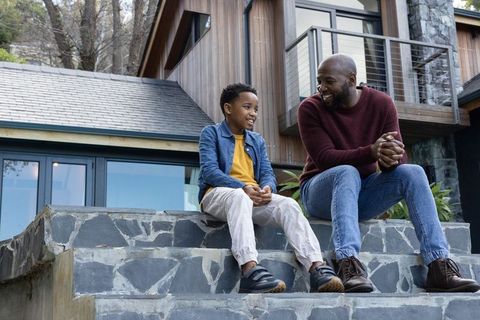 African american father and son sharing warm conversation on modern stone steps