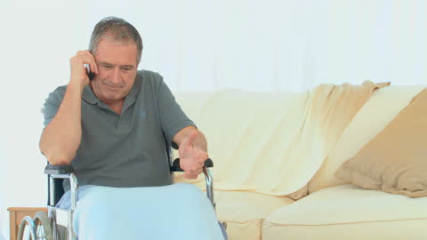 Senior Man in Wheelchair Talking on Phone at Home