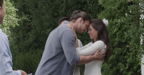 Newlyweds Embrace at Outdoor Wedding Amidst Lush Greenery