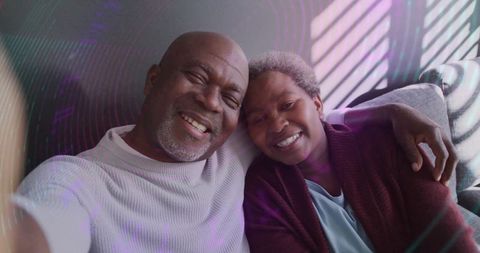 Smiling Senior Couple Taking Selfie on Light Sofa with Shadows