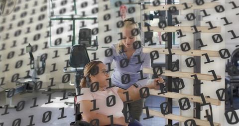 Trainer helping wheelchair client reaching stall bars during rehabilitation session