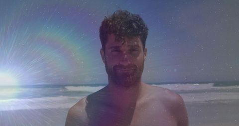 Shirtless man standing on sunny beach with sunburst lens flare and cinematic grain