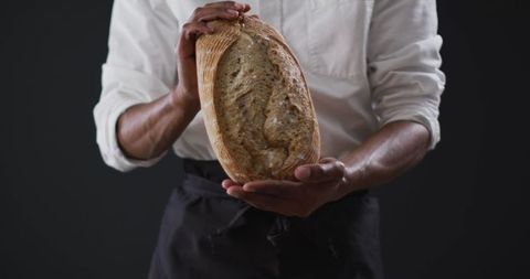 Baker presenting freshly baked whole grain bread loaf