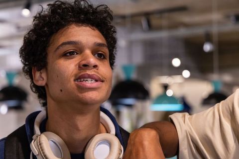 Teen friends sharing headphones in modern cafe with conversation, bokeh lights, urban teal tones