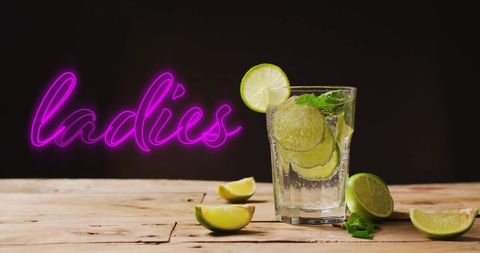 Neon Ladies Sign Over Refreshing Lime Cocktail on Wooden Table
