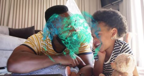 Father and daughter watching teal hologram while playing on tablet at home smiling bonding