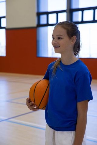 Young Girl Preparing to Play Basketball on Indoor Court