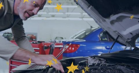 Senior mechanic inspecting car engine with laptop in garage with gold star overlay