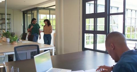 African american coworkers walking and chatting in modern open-plan coworking office