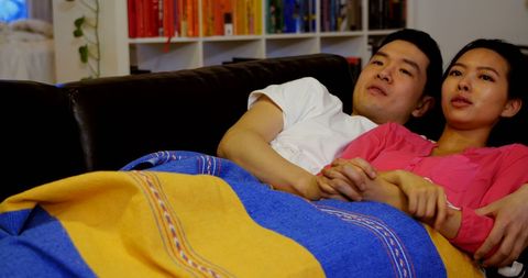 Couple Relaxing on Sofa with Cozy Blanket in Living Room