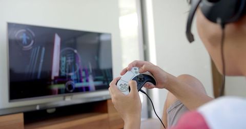 Focused Gamer Playing Console Video Game with Headphones