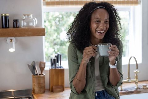 African american woman enjoying morning coffee in cozy rustic kitchen, smiling lifestyle
