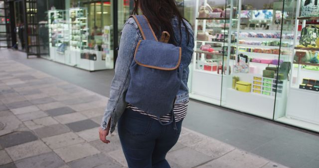 Rear midsection of plus size caucasian woman wearing backpack walking in city street. City living and modern urban lifestyle.