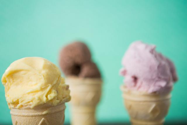 Close-up of vanilla ice cream cone and strawberry and chocolate icecream in background