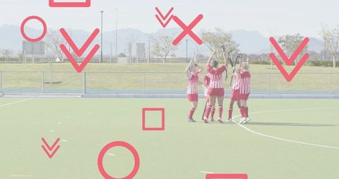 Uniting women field hockey team celebrating victory on green turf with raised sticks