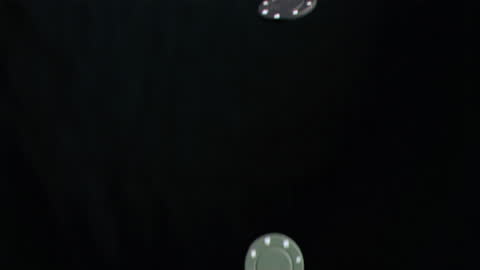 Falling Poker Chips Against Black Background in Slow Motion