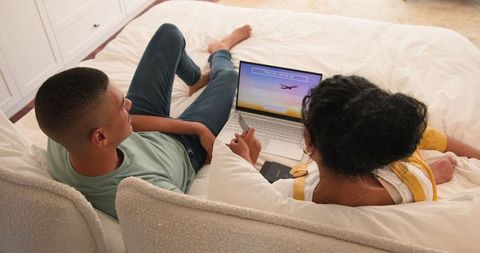 Couple planning vacation online comfortably from bedroom