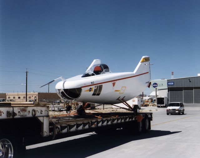 After the grounding of the M2-F1 in 1966, it was kept in outside storage on the Dryden complex. After several years, its fabric and plywood structure was damaged by the sun and weather. Restoration of the vehicle began in February 1994 under the leadership of NASA retiree Dick Fischer, with other retirees who had originally worked on the M2-F1's construction and flight research three decades before also participating. The photo shows the now-restored M2-F1 returning to the site of its flight research, now called the Dryden Flight Research Center, on 22 August 1997.