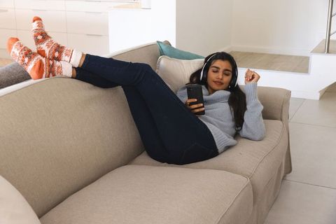 Young Woman Relaxing on a Sofa Listening to Music