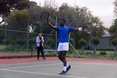 Tennis practice player swinging racket on outdoor court during coaching session