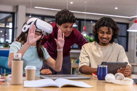 Young diverse team testing vr headset and collaborating with tablet in modern coworking space