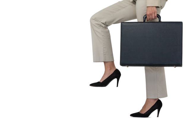 This image depicts a businesswoman in professional attire climbing steps while holding a briefcase. The focus is on her legs and the briefcase, symbolizing ambition, determination, and career progression. Ideal for use in business-related content, career development articles, corporate presentations, and motivational materials.