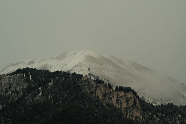 Snow-covered mountain with a foggy atmosphere is perfect for conveying winter redensityy, natural beauty and tranquility in outdoor adventure content, travel blogs, or nature documentaries.