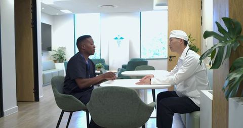Multicultural medical team discussing patient care in modern clinic lounge with plants