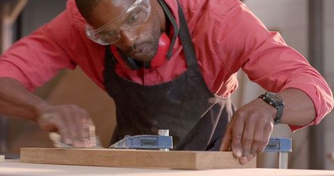 Skilled african american craftsman sanding wood piece in workshop