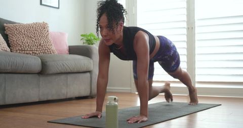 African american woman performing mountain-climber exercise on yoga mat at home