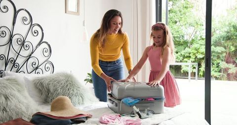Mother and Daughter Packing for Summer Vacation on Bed