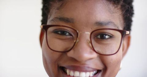 Smiling young professional wearing brown glasses close-up headshot with gold bridge