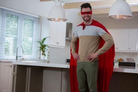 Confident Man in Red Cape and Mask Smiling in Modern Kitchen