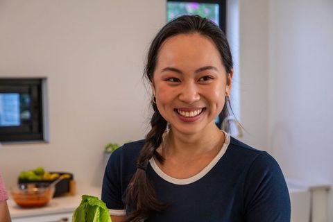 Woman smiling holding lettuce in modern kitchen with fresh produce