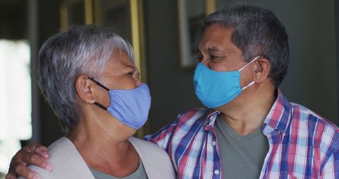 Senior Couple Embracing While Wearing Masks at Home