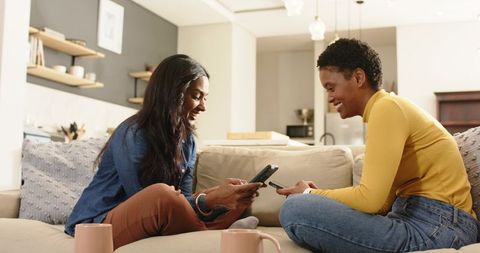 Diverse Friends Sharing Smartphones in Cozy Living Room