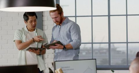 Diverse Professionals Collaborating with Digital Tablets in Modern Office