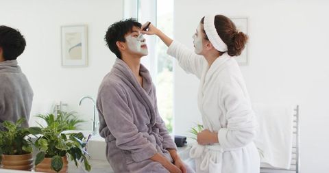 Couple applying face masks together in bright bathroom morning self-care routine