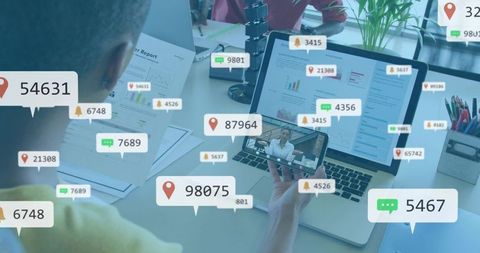 Man holding smartphone with live notification bubbles over laptop analytics and dashboard
