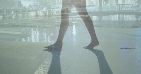 Bare feet walking along wet seafront plaza with double exposure urban reflections